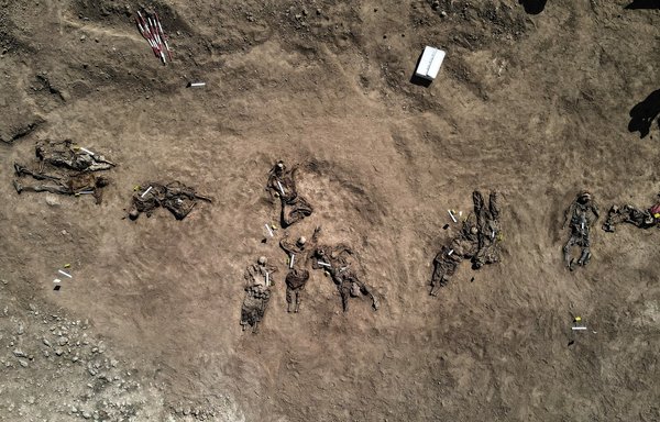 صورة جوية التقطت يوم 13 حزيران/يونيو تظهر فيها رفات بشرية يقال إنها لضحايا مذبحة سجن بادوش التي ارتكبها تنظيم داعش عام 2014، وذلك بعد إخراجها من مقبرة جماعية في قرية بادوش شمال غربي محافظة الموصل في شمالي العراق. [زيد العبيدي/وكالة الصحافة الفرنسية]