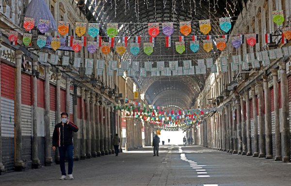 أشخاص يدخلون إلى سوق الحميدية المغطى في العاصمة السورية دمشق والذي يعود تاريخه إلى قرن من الزمن. [لؤي بشارة/وكالة الصحافة الفرنسية]