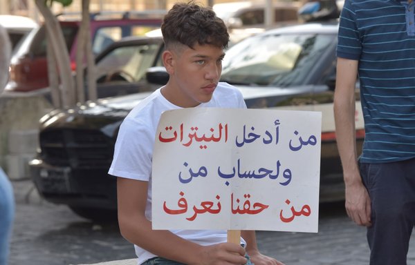 شاب لبناني يرفع لافتة خلال وقفة لإحياء ذكرى ضحايا الانفجار الذي وقع في 4 تموز/يوليو بمرفأ بيروت. [زياد حاتم]