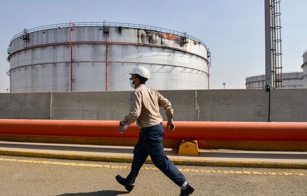 An employee at the Saudi Aramco oil facility, walks near a damaged silo at the plant in Jeddah on November 24. Yemen's Houthis launched a missile attack on the facility the day before, triggering an explosion and a fire in a fuel tank. [Fayez Nureldine/AFP]