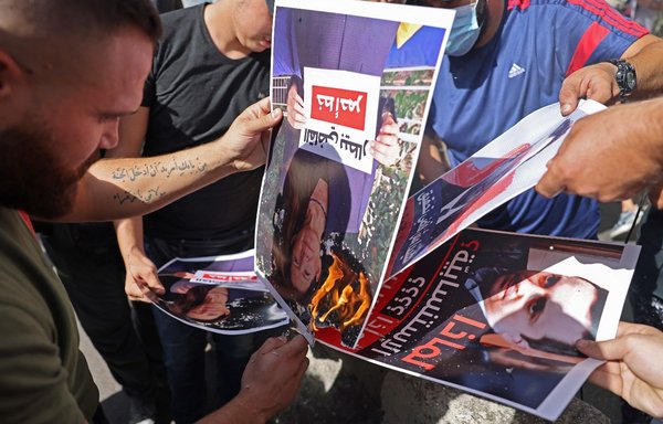 حامیان حزب‌الله و جنبش امل ٢٢ مهرماه، در جریان تجمعی در نزدیکی کاخ دادگستری در بیروت که خواسته آن برکناری قاضی طارق بیطار، بازپرس اصلی انفجار بیروت بود، تصویر او را به آتش می‌کشند. [جوزف عید/خبرگزاری فرانسه]