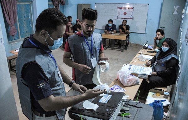 Iraqi election officials print out the electronic count of votes at a polling station in the southern city of Nasiriyah in Dhi Qar province on October 10. [Asaad Niazi/AFP]