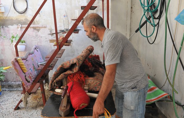 ورث اللاجئ السوري عبد الوهاب الشامي حرفة إصلاح السجاد وترميمه، وحول قسما من سطيحة الغرفة التي تؤوي عائلته إلى ورشة لإصلاح السجاد. [زياد حاتم]