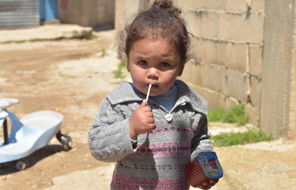 A small girl drinks juice in the Saadnayel displacement camp in the Bekaa Valley in autumn 2021. [Ziad Hatem]