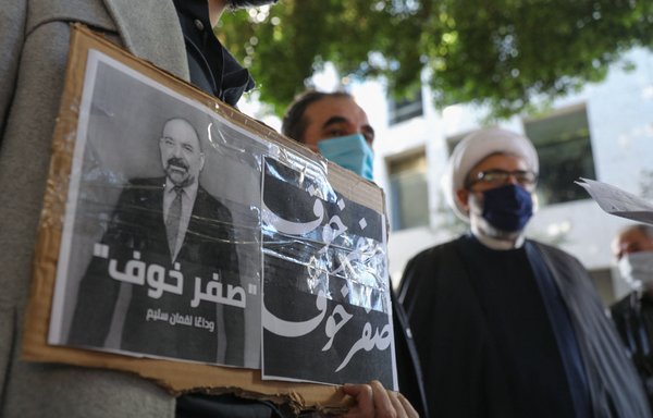 Lebanese activists lift placards bearing the portrait of slain activist and intellectual Lokman Slim and the Arabic slogan 'zero fear' at a demonstration in downtown Beirut on February 9. [Anwar Amro/AFP]