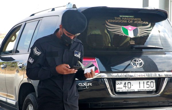 Jordanian police check documents at the Jaber/Nassib border post between Jordan and Syria on September 29, the day of its reopening. [Khalil Mazraawi/AFP]