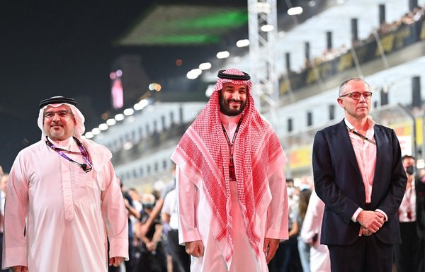 محمد بن سلمان آل سعود، ولیعهد عربستان سعودی (میانی) و استفانو دومنیکالی، مدیر عامل گروه فرمول یک (راست) ١٤ آذر قبل از آغاز مسابقه جایزه بزرگ فرمول یک عربستان سعودی روی منطقه شروع در پیست کورنیش جده ایستاده‌اند. [آندری ایساکوویچ/ پول/خبرگزاری فرانسه]