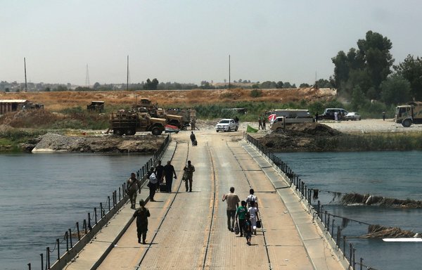 عراقيون يعبرون جسرا يربط بين غرب وشرق الموصل في 13 تموز/يوليو 2017، بعد أيام قليلة من إعلان الحكومة "تحرير" المدينة المحاصرة من داعش. [صافين حامد/وكالة الصحافة الفرنسية]