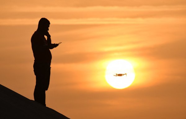 A man flies a drone at sunrise near the city of Nasiriyah in Iraq's southern Dhi Qar province on April 24. [Asaad Niazi/AFP]