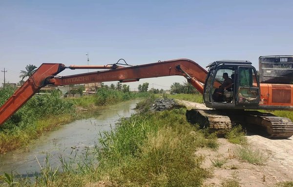 An Iraqi man clears mud and weeds on June 21 from a tributary in Diyala province to ensure the smooth flow of water to agricultural lands. [Iraqi Ministry of Water Resources]