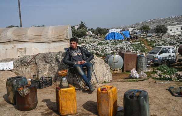 یک جوان سوری روز ۲۰ اسفند ۱۳۹۸ در شهر سرمین، واقع در حدود ۸ کیلومتری جنوب شرقی شهر ادلب در شمال غربی سوریه، در حال فروش سوخت است. [اوزن کوزه/ خبرگزاری فرانسه]