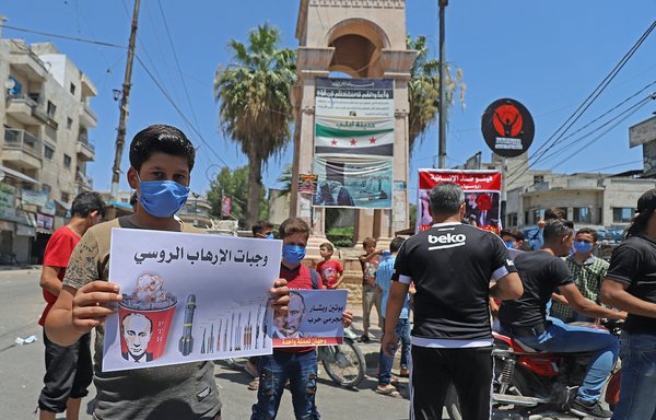 محتجون سوريون في مدينة إدلب يحملون لافتات تعبر عن معارضتهم لمحاولة روسيا، حليف النظام السوري، خفض المعونات التي تنقل عبر الحدود إلى الملايين في شمال غرب البلاد يوم 10 تموز/يوليو 2020. [عبد العزيز كيتاز/وكالة الصحافة الفرنسية]