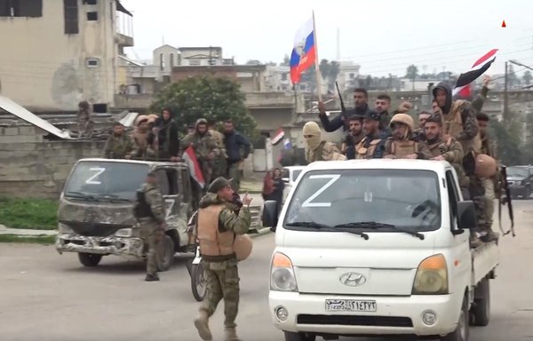 در یک راهپیمایی خودرویی برای حمایت از پوتین، سربازان سوری پرچم روسیه به دست گرفته‌اند و نماد «Z» روسی را نشان می‌دهند. [تلویزیون زوزدا]