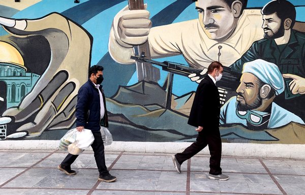 چند مرد ایرانی روز ۱۸ اسفند از برابر یک نقاشی دیواری در تهران عبور می کنند. مردم ایران از حکومت جمهوری اسلامی می خواهند که در برنامه های خود مبنی بر تکیه بر تجارت با شرق به عنوان راه حلی برای مشکلات اقتصادی کنونی کشورشان، تجدیدنظر کند. [عطا کناره/خبرگزاری فرانسه]