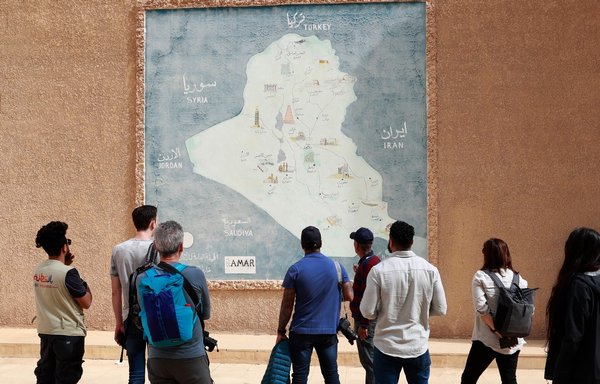 گردشگران خارجی در روز ۱۶ اسفند در جریان بازدید از شهر باستانی بابل به نقشه عراق نگاه می کنند. [احمد الربیعی/ خبرگزاری فرانسه]