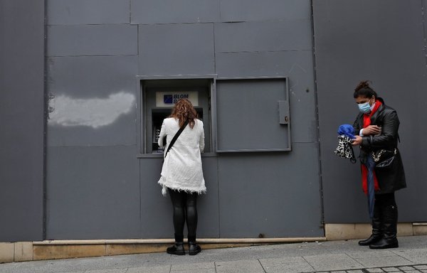 A woman withdraws money from an automated teller machine in Beirut on December 1, 2020. [Joseph Eid/AFP]