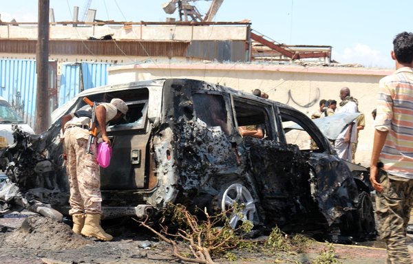 Yemeni security forces and rescue teams gather around the ruins of a car following an explosion in Aden on October 10, in which five people were killed, including three journalists. [Saleh al-Obeidi/AFP]