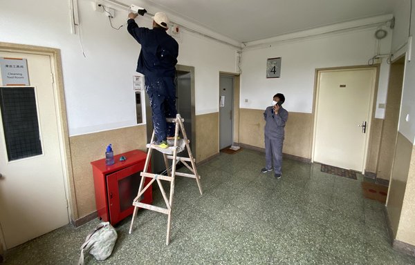 A Chinese worker May 3, 2020, in Beijing adjusts a surveillance camera outside the home of a journalist placed under quarantine after he had visited Wuhan. [Leo Ramirez/AFP]