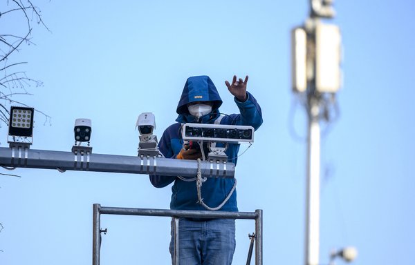 A worker installs closed circuit TV cameras in Beijing on December 16, 2020. [Noel Celis/AFP]