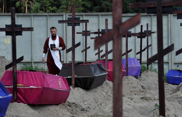 An Orthodox priest in Bucha, Ukraine, on August 17 holds a funeral ceremony for 20 unidentified Ukrainians killed in February-March 2022. Russian forces are accused of summary executions, enforced disappearances and torture during their occupation of the town. [Sergei Zhuzavkov/AFP]