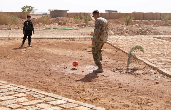 عنصر من التحالف الدولي يمارس رياضة كرة القدم مع فتى في مخيم الركبان يوم 10 كانون الثاني/يناير. [جيش مغاوير الثورة]