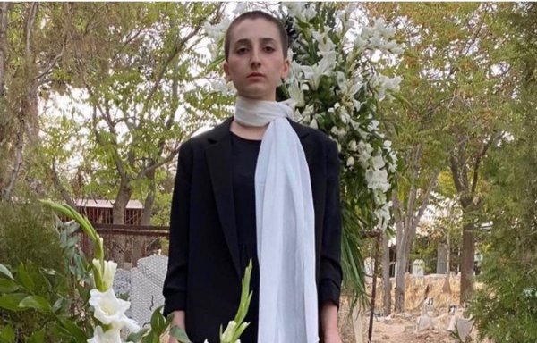 شابة قتلت والدتها في تظاهرات أيلول/سبتمبر بإيران، تقف فوق قبر هذه الأخيرة ماسكة بشعرها الذي قصته. وقد وضعت صورة والدتها فوق القبر. [مواقع التواصل الاجتماعي]