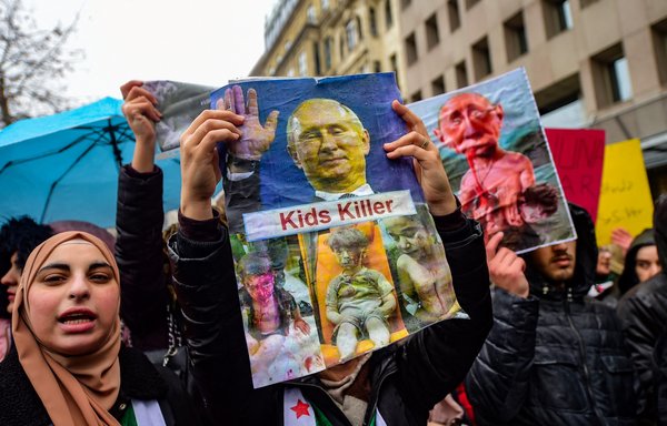 Protesters hold a placard reading 'Kids killer' bearing photographs of Russian President Vladimir Putin and wounded children during a protest against the Russian-backed Syrian military operation in Idlib near the Russian Consulate in Istanbul, on December 28, 2019. [Yasin Akgul/AFP]