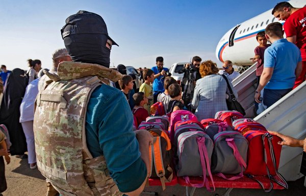A group of children, among 38 from families of suspected ISIS fighters, board a plane before being repatriated to Russia, at the airport of the city of Qamishli in Syria's northeastern al-Hasakeh province, on October 20. [Delil Souleiman/AFP]