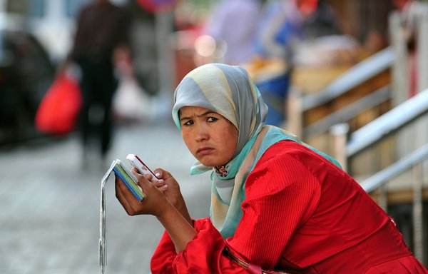 امرأة مسلمة تستخدم هاتفها الخلوي في شينجيانغ بالصين. [فريديريك ج. براون/وكالة الصحافة الفرنسية]
