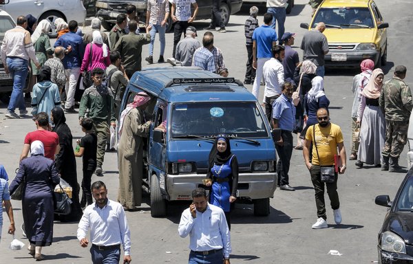 A man stands beside a minibus for hire in Damascus on July 12, 2021, after the Syrian regime announced a steep increase in fuel prices. Prices have continued to climb, amid shortages, sparking protests. [Louai Beshara/AFP]