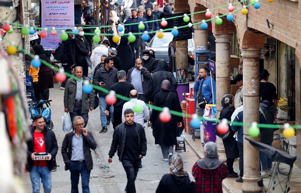 People walk in a commercial area in Tehran on February 21. [ATTA KENARE / AFP]