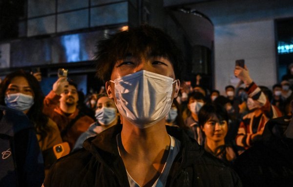 People gather on a street in Shanghai on November 27, 2022, where protests took place following a deadly fire in Urumqi, the capital of the Xinjiang region. [Hector RETAMAL / AFP]
