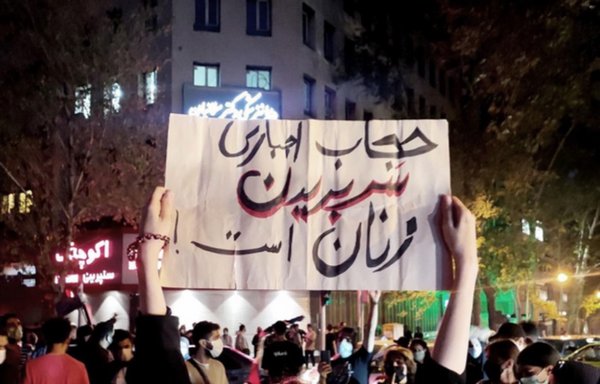 An Iranian woman holds up a sign saying 'Mandatory hair covering is like cutting women's head off!' at a recent protest in Iran. [Iran International]