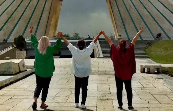 Women without head coverings raise their arms in front of Tehran's iconic Azadi Tower. [Social media]