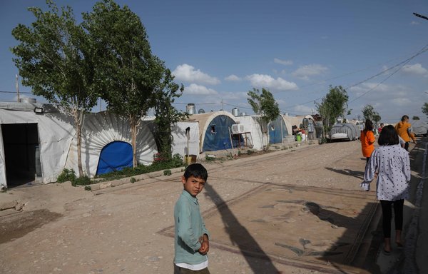 إيزيديون نازحون يقفون إلى جوار خيمهم في مخيم جمشكو للنازحين داخليا في مدينة زاخو شمال المنطقة الكردية بالعراق، يوم 5 أيار/مايو. [صافين أحمد/وكالة الصحافة الفرنسية]