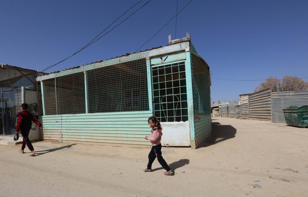 Syrian refugee children walk past a makeshift structure at al-Zaatari refugee camp on March 13. [Mohammad Abu Ghosh]