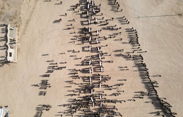 صورة التقطت من الجو لمشيعين يحملون توابيت خلال مراسم تشييع جماعية لضحايا داعش الأيزيديين الذين عثر على رفاتهم في مقبرة جماعية بمنطقة كوجو في سنجار يوم 9 كانون الأول/ديسمبر 2021. [زيد العبيدي/وكالة الصحافة الفرنسية]