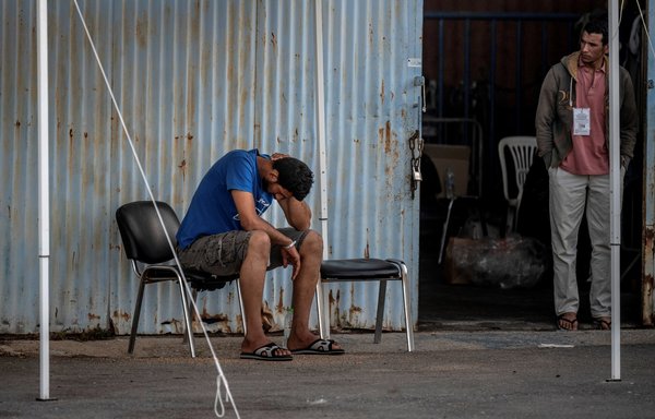 Survivors of a shipwreck stand at a warehouse in Kalamata, Greece, on June 15, after a boat carrying dozens of migrants, including more than 100 Syrians, sank in international waters in the Ionian Sea. [Angelos Tzortzinis/AFP]