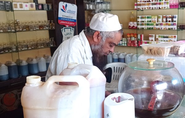 بائع عسل يحضّر طلبية لأحد العملاء في متجره بصنعاء في حزيران/يونيو. [هيثم محمد/المشارق]