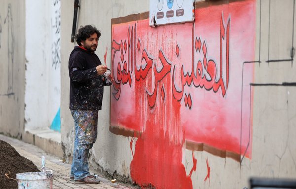 روز ۱۶ دی ۱۴۰۰ در شهر اعزاز در حلب در مراسمی که خانواده‌ها و بستگان بازداشت‌شدگان و ناپدیدشدگان با شرکت در تجمعی خواستار دریافت اطلاعاتی از عزیزانشان شدند، عزیز اسمر، هنرمند سوری، یک نقاشی دیواری را ترسیم می‌کند که روی آن نوشته شده است: «بازداشت‌شدگان زخمِ باز ما هستند.» [بکر القاسم/ خبرگزاری فرانسه]