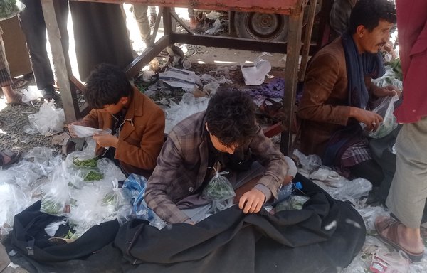 Jalal Nasser (left), who dropped out of school to help his father provide for his family's needs, sells qat in Sanaa. [Haytham Mohammed/Al-Mashareq]