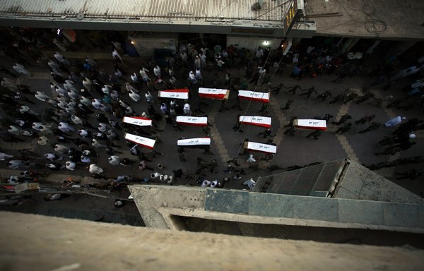 جنود عراقيون يحملون نعوشا تضم رفات 10 من زملائهم وقد قتلوا في مجزرة معسكر سبايكر عام 2014، وذلك خلال مراسم تشييعهم بالنجف يوم 1 تموز/يوليو 2015. وقد تم تسليم الرفات إلى الأقارب عقب أسابيع من الفحوصات للتحقق من هوياتهم عبر اختبارات الحمض النووي. [حيدر حمداني/وكالة الصحافة الفرنسية]