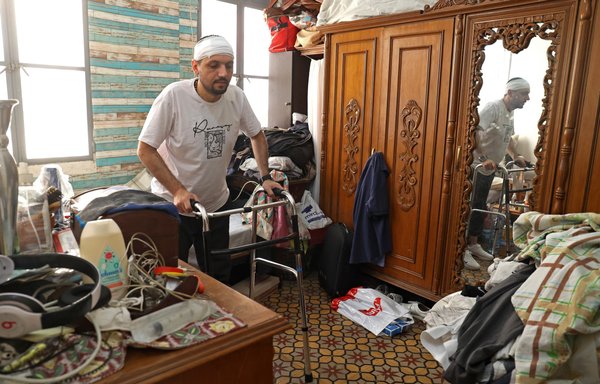 Dani Salameh, a Beirut multiple sclerosis patient whose symptoms have worsened since his injury in the August 4, 2020, port explosion, uses a walker to move around his house July 22. [Anwar Amro/AFP]
